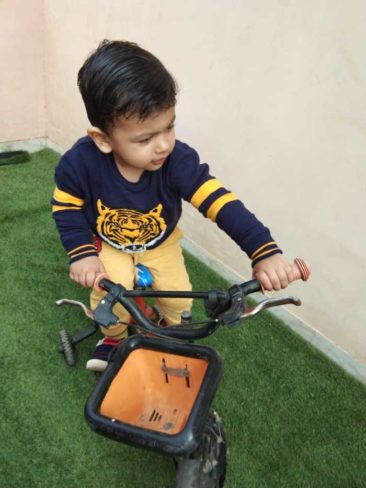 kid riding a bicycle at kindergarten mums lap.in